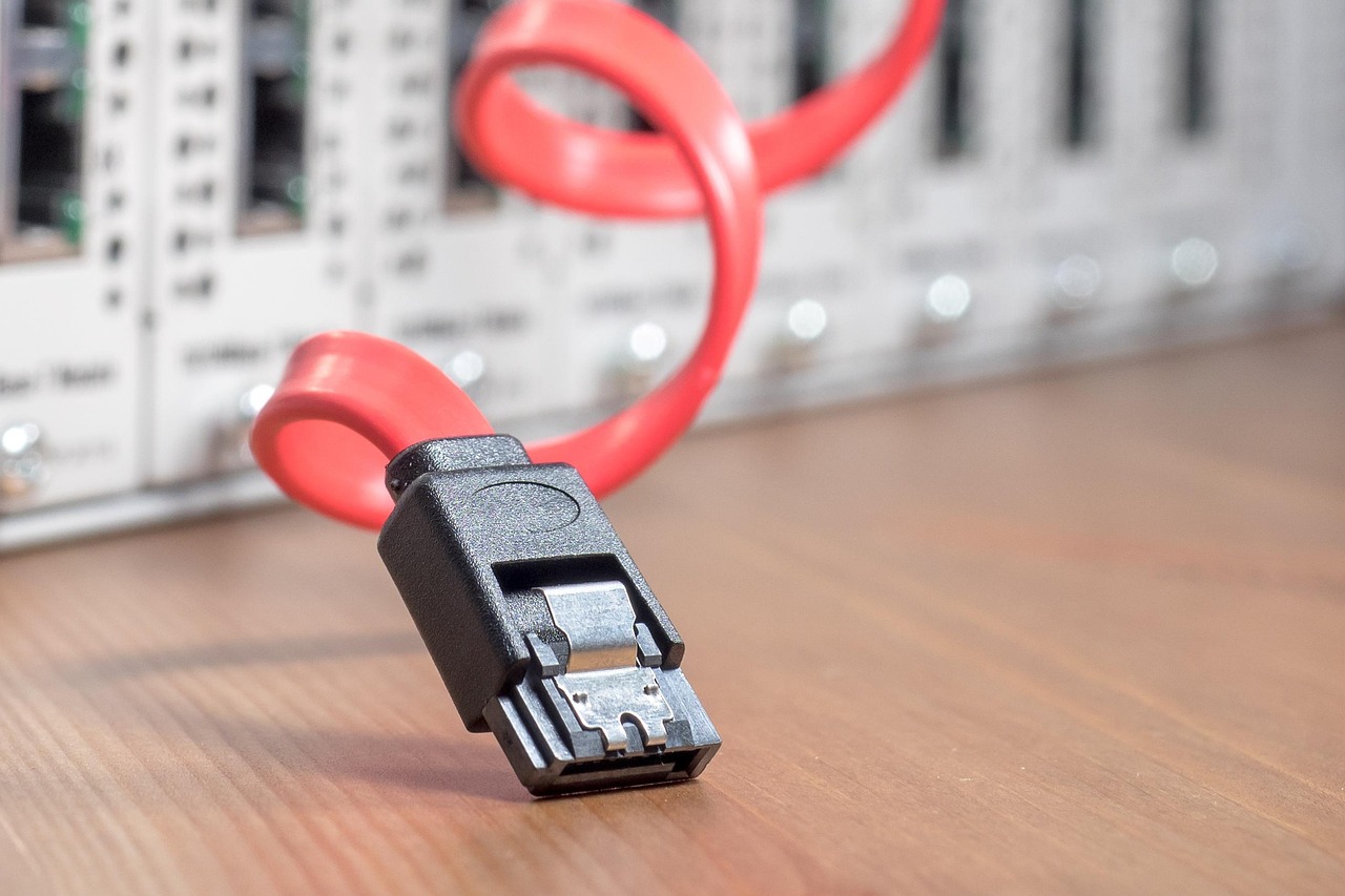 Un cavo dati rosso davanti ad apparecchiature di rete - Tor inoltra il tuo traffico attraverso più server prima che raggiunga un sito.