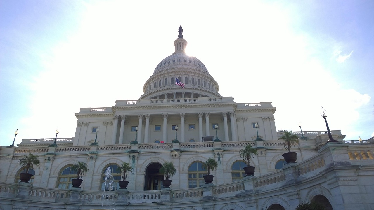 El Capitolio de Estados Unidos en Washington, D.C., con su cúpula blanca coronada por una estatua y una bandera estadounidense ondeando delante bajo un cielo luminoso - una ley federal de privacidad se debate aquí desde hace años, pero no se ha aprobado como texto único e integral, dejando que actúen los estados.